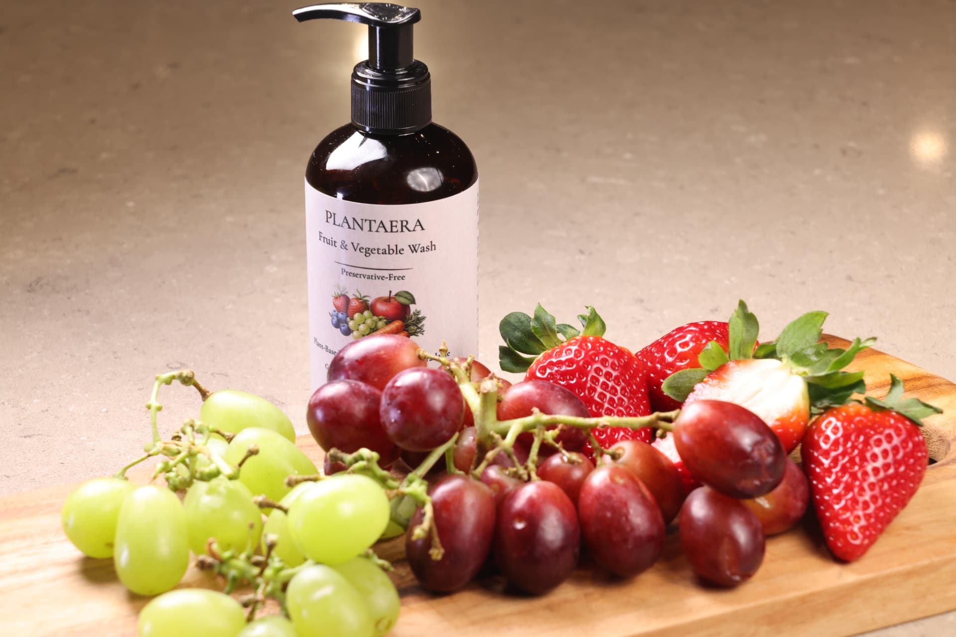Plantaera bottle with fresh strawberries, grapes and stone fruit on a wooden board
